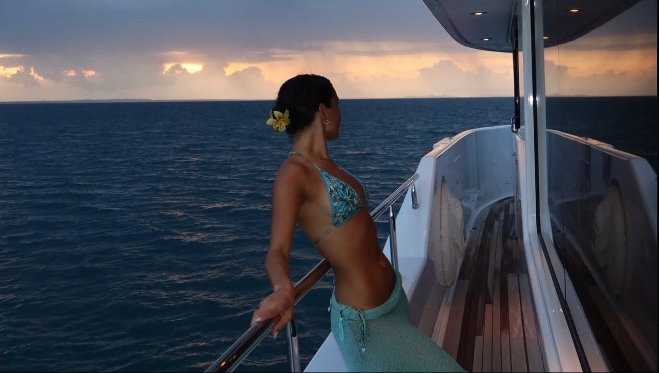Woman on a boat deck looking at the ocean during sunset
